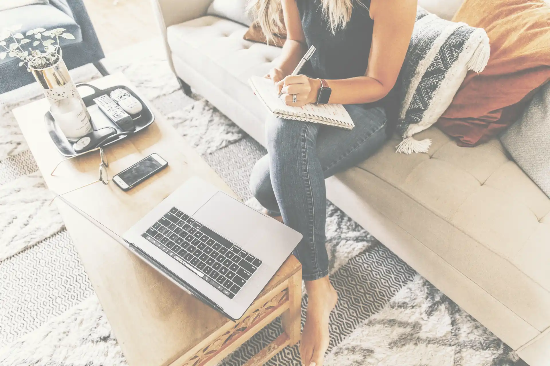 Self Employed woman with computer writing on a note pad